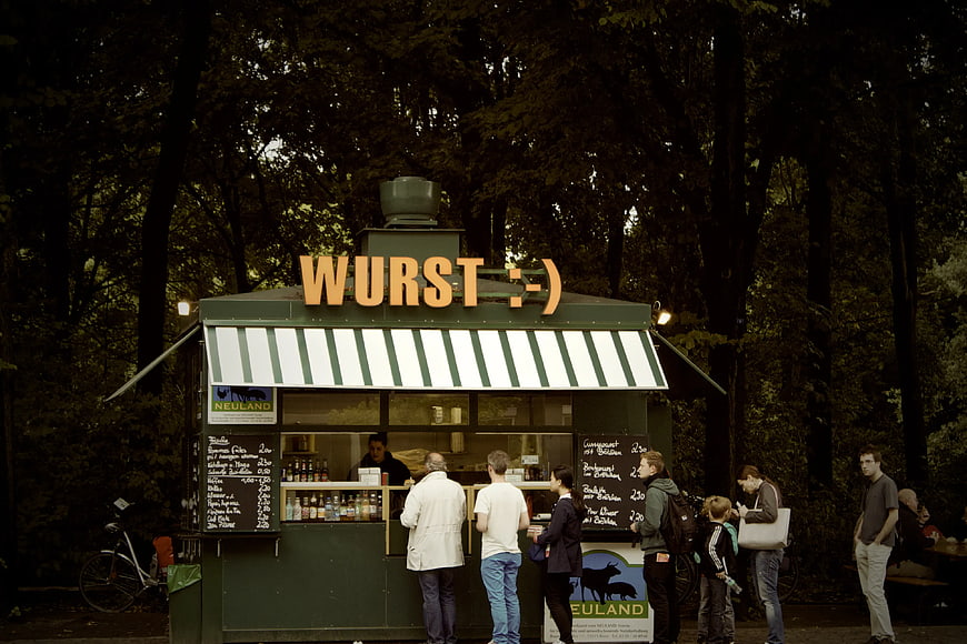 People buying sausages at a Wurst food stall in a park
