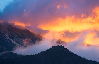 Dramatic Sunset Over Mountain Peaks with Fog and Clouds
