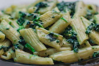 Close-up of creamy penne pasta with spinach and herbs