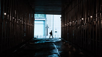 Silhouette of Man Walking Through Dark Urban Tunnel