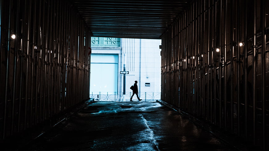 Silhouette of Man Walking Through Dark Urban Tunnel