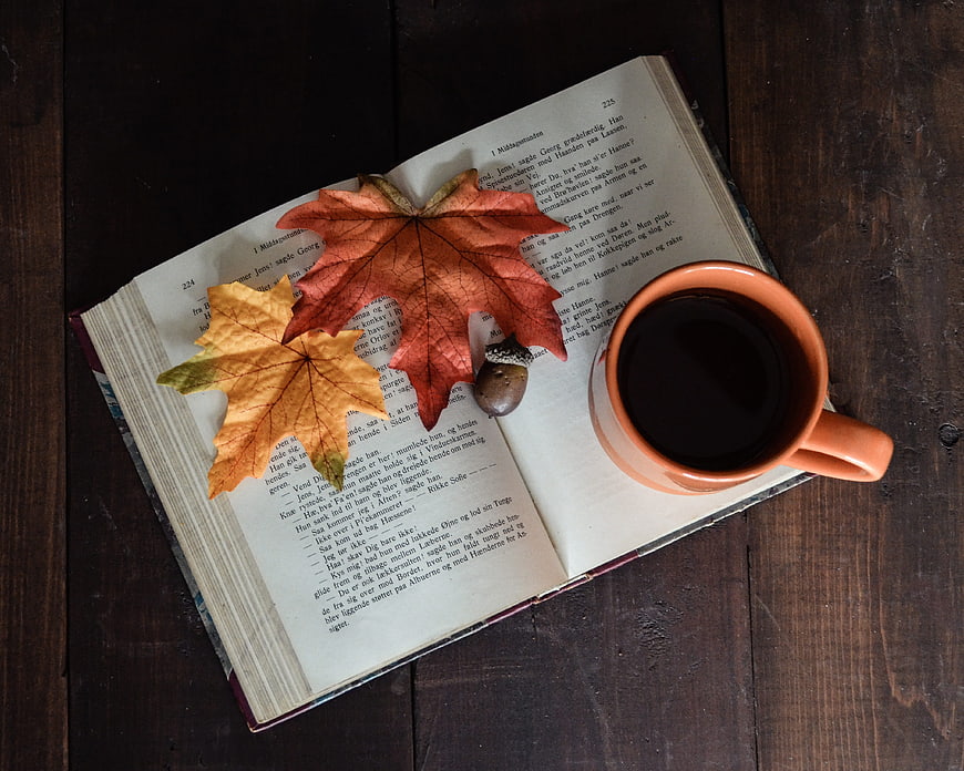 Autumn flat lay with open book, coffee, and maple leaves