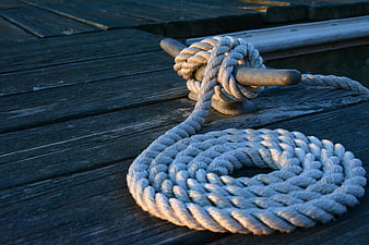 Coiled white rope tied to wooden bollard on deck