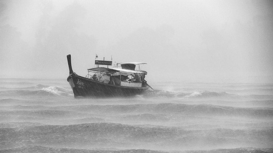 Longtail boat battling rough seas in black and white