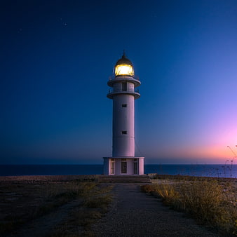 Illuminated Lighthouse at Twilight on Coastal Path