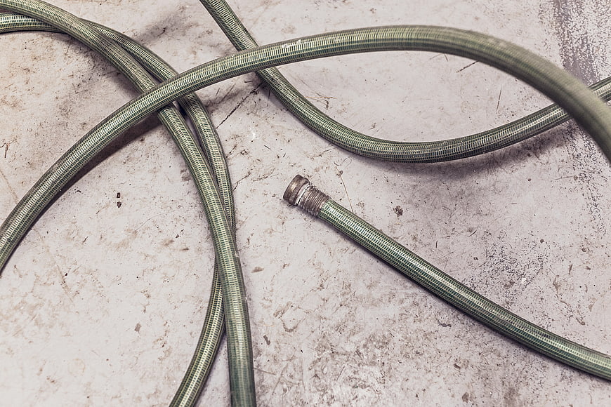 Green garden hose on concrete background