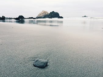 Minimalist Beach Scene with Smooth Sand and Distant Rocks