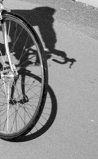 Black and white bicycle wheel shadow on pavement