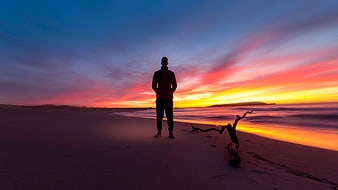 Man Standing on Beach at Vibrant Sunset