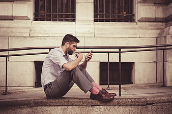 Man sitting on steps listening to music on smartphone