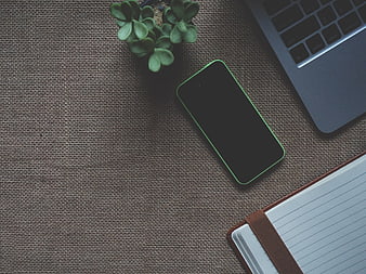 Flat lay workspace with smartphone, laptop, and notebook on textured background