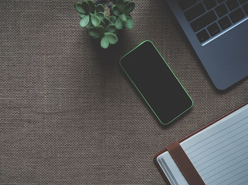 Flat lay workspace with smartphone, laptop, and notebook on textured background