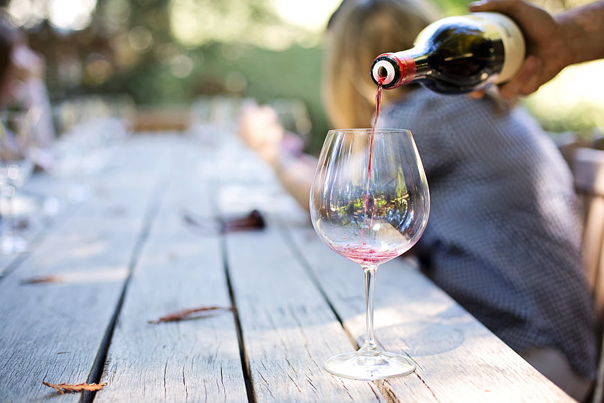 Pouring Red Wine into Glass on Wooden Table