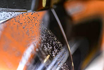 Close-up of water droplets on a glossy orange car surface