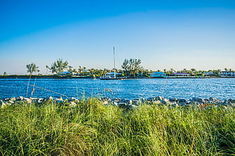 Sailboat anchored in tropical inlet with coastal homes