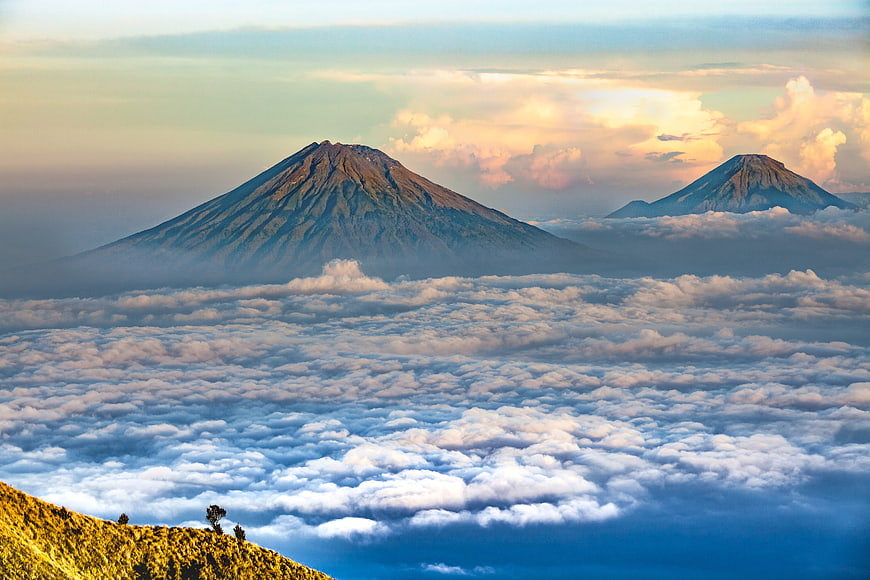 Volcanic Peaks Rising Above Sea of Clouds at Sunrise in Indonesia