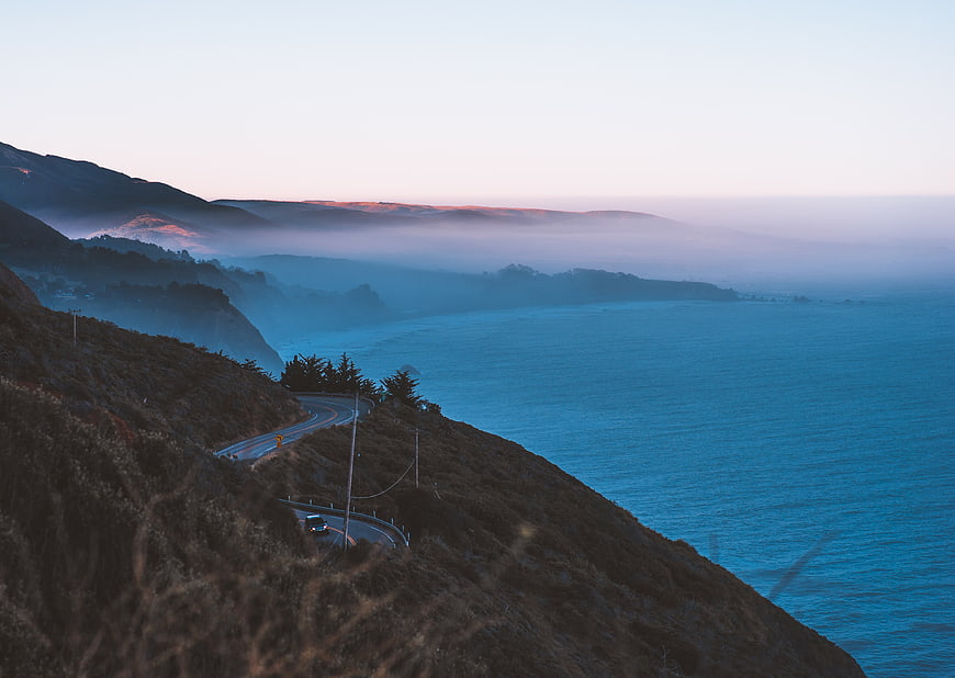 Winding coastal highway at sunrise with ocean view