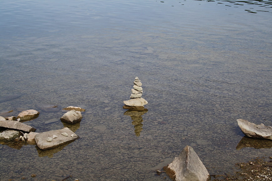 Balanced stone cairn in clear shallow lake water