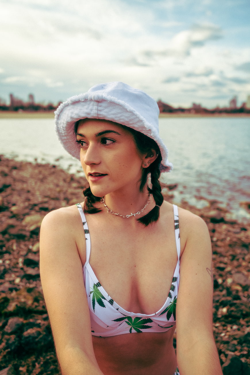 Young woman in bikini and bucket hat by the water