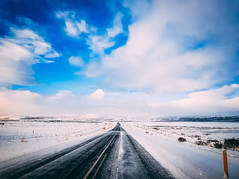 Snowy Winter Road Stretching to Horizon Under Blue Sky
