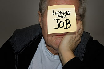 Senior man holding looking for a job sticky note over face