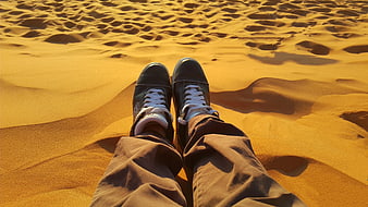 First-person view of sneakers on golden desert sand