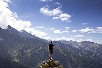 Man standing on mountain peak looking at scenic landscape