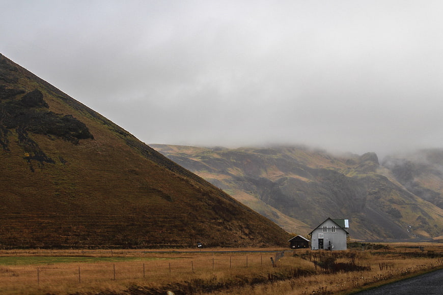 Lone white house in misty mountain valley landscape