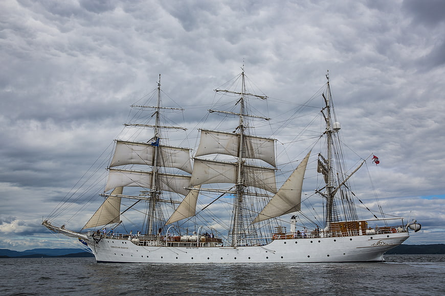 White Tall Ship Sailing on Ocean Under Cloudy Sky