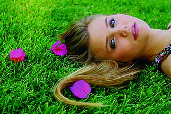 Blonde Woman Lying on Green Grass with Pink Flowers