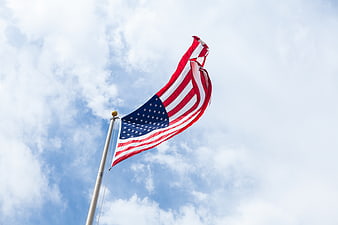 American Flag Waving Against Blue Sky with Clouds