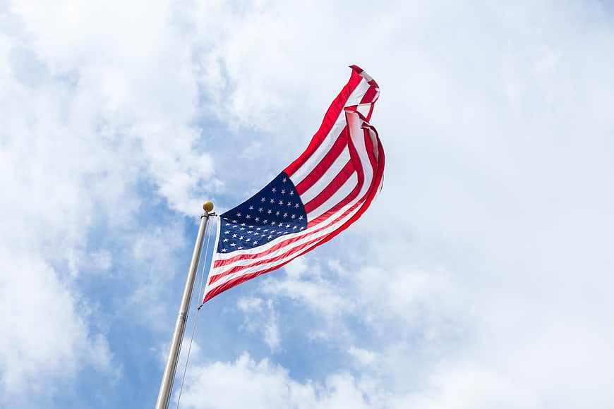 American Flag Waving Against Blue Sky with Clouds