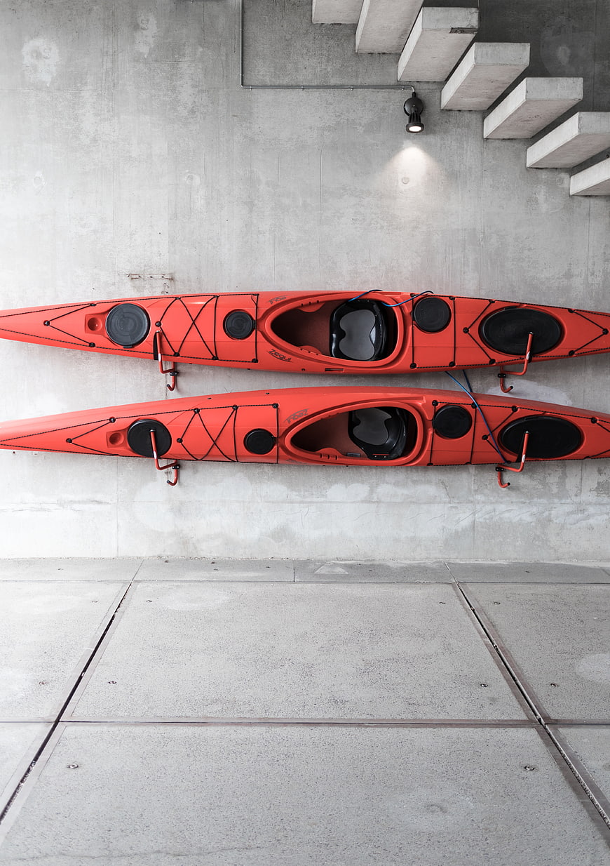 Two orange kayaks mounted on concrete wall