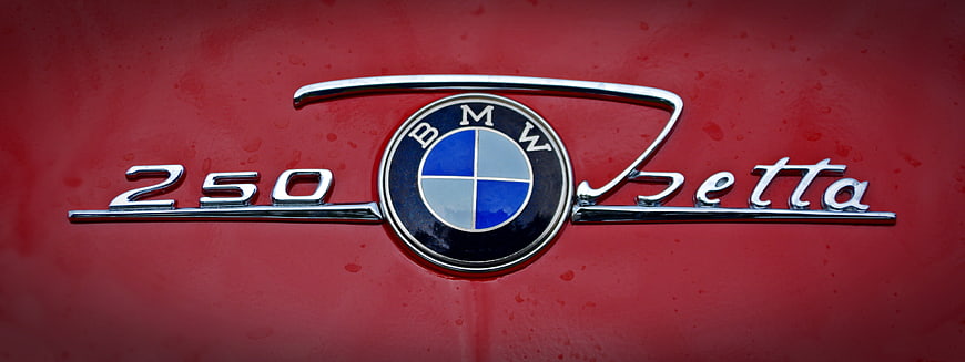 Close-up of BMW 250 Isetta emblem on red car body