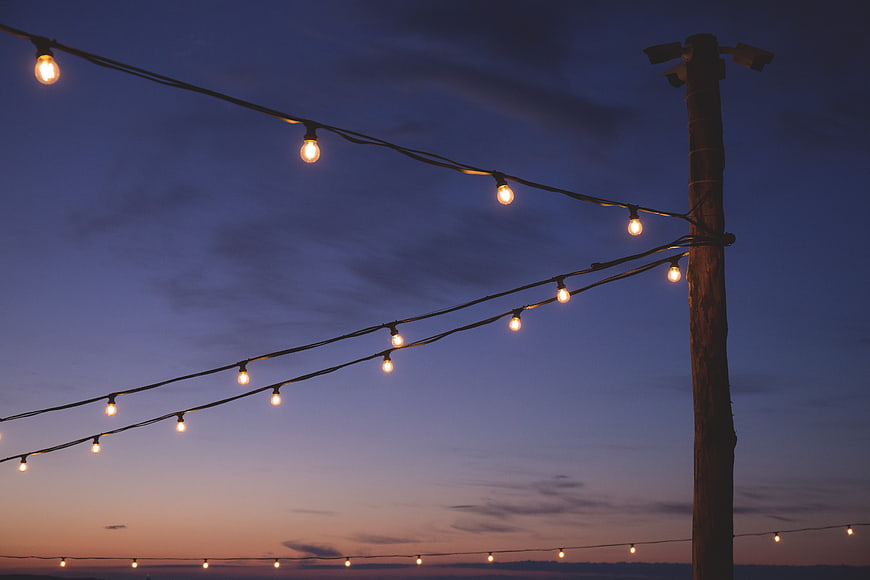 String lights on wooden pole against twilight sky