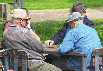 Senior Men Playing Dominoes At Park Table