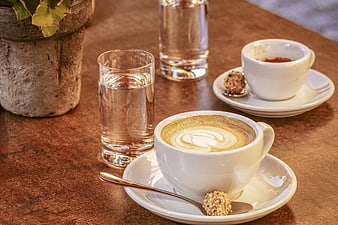 Cappuccino with Latte Art and Water Glasses on Rustic Wooden Table