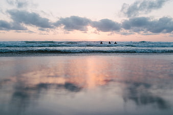 Surfers waiting for waves at sunset on a calm beach