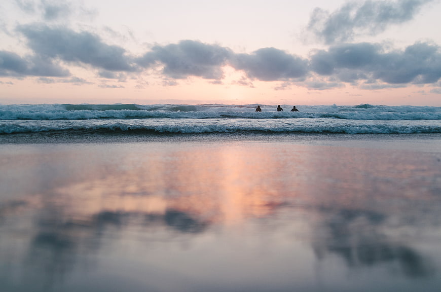 Surfers waiting for waves at sunset on a calm beach