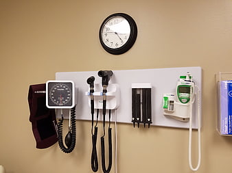 Medical examination room wall with diagnostic equipment and clock