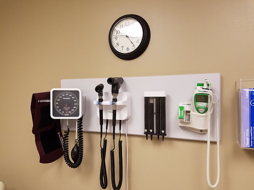 Medical examination room wall with diagnostic equipment and clock