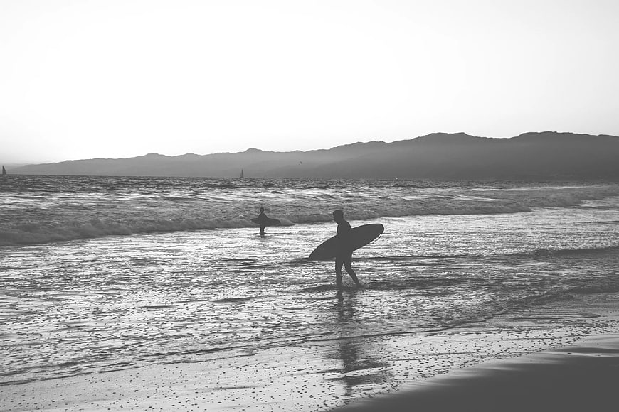 Surfer Silhouette Walking on Beach with Surfboard