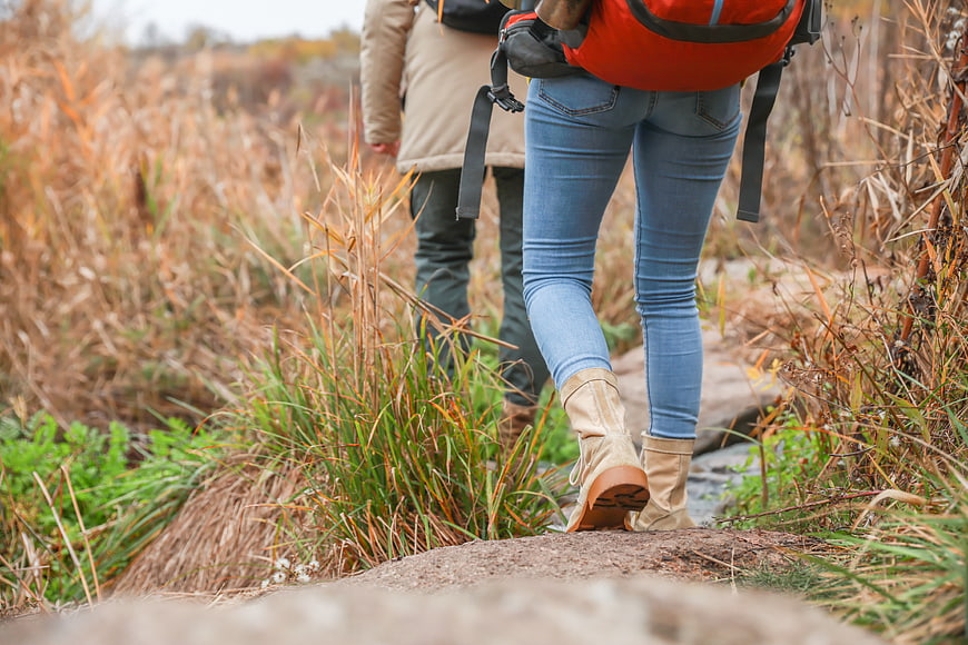 Couple hiking on trail with backpacks in autumn