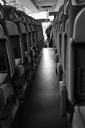 Black and white view of empty bus aisle with driver