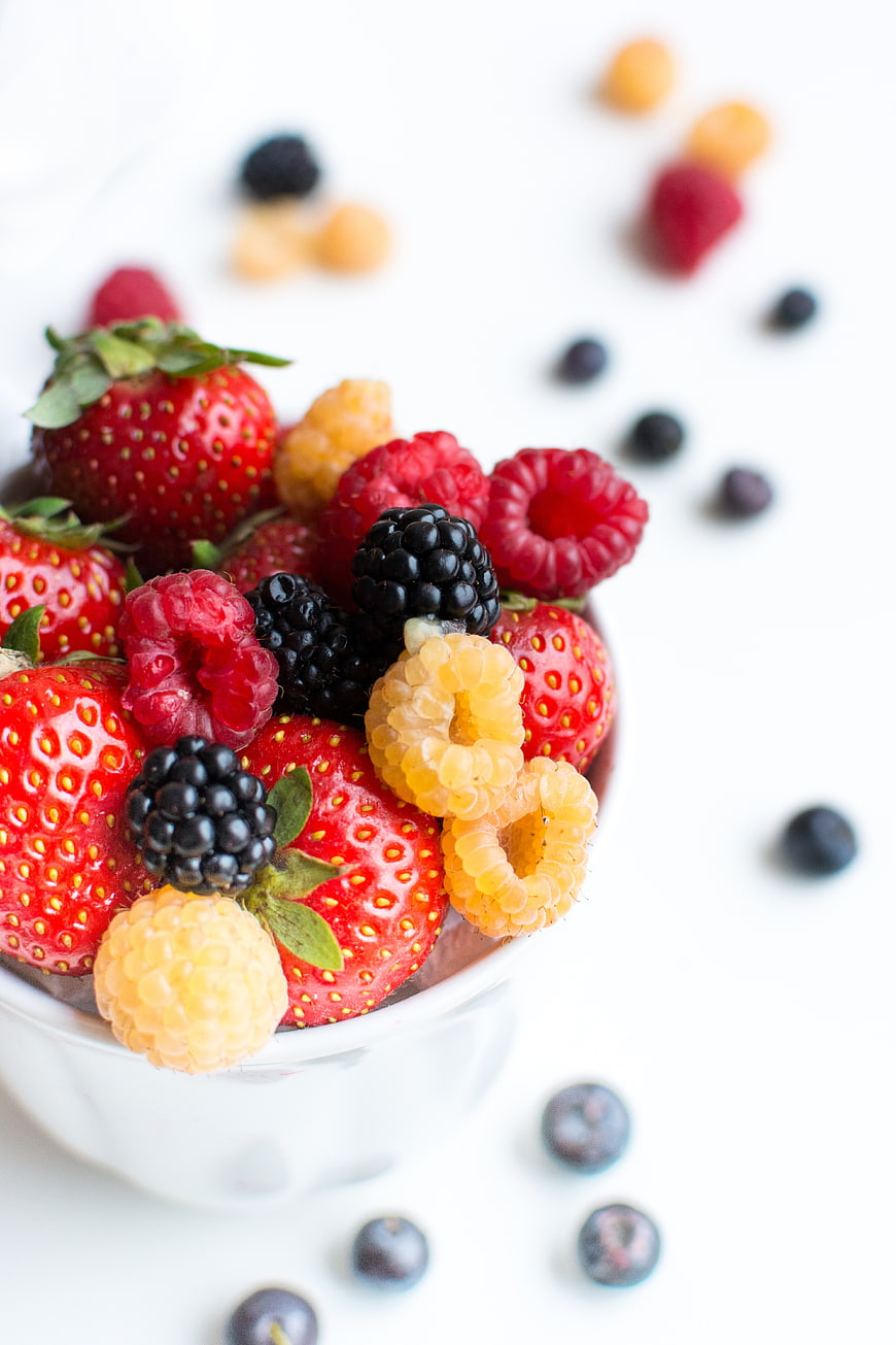 Fresh mixed berries in a white bowl on white background