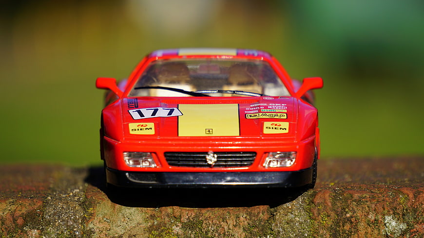 Red Ferrari Model Car on Mossy Surface