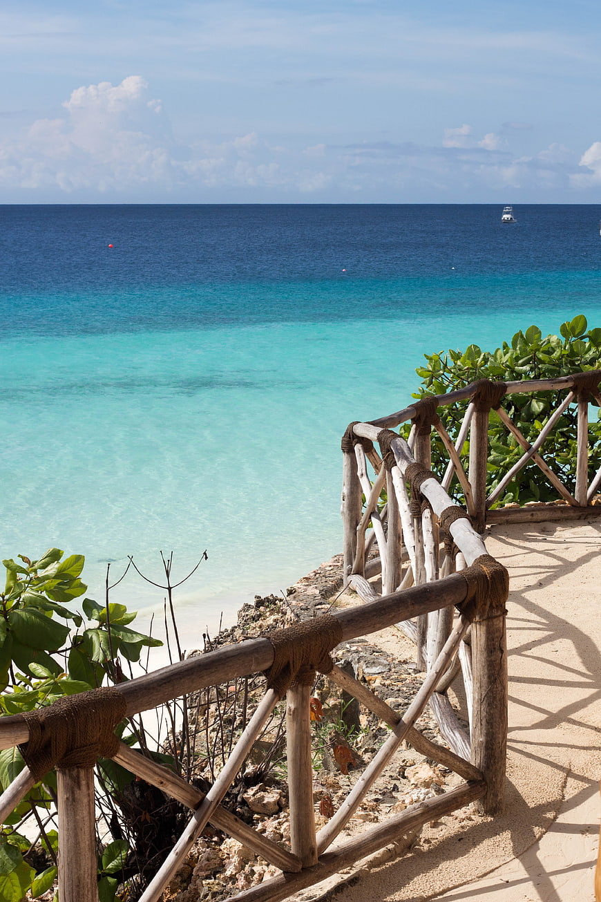 Tropical Beach View With Wooden Railing And Turquoise Ocean Water