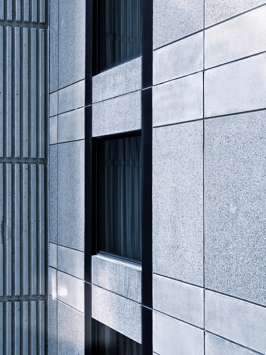 Modern gray stone building facade with vertical windows