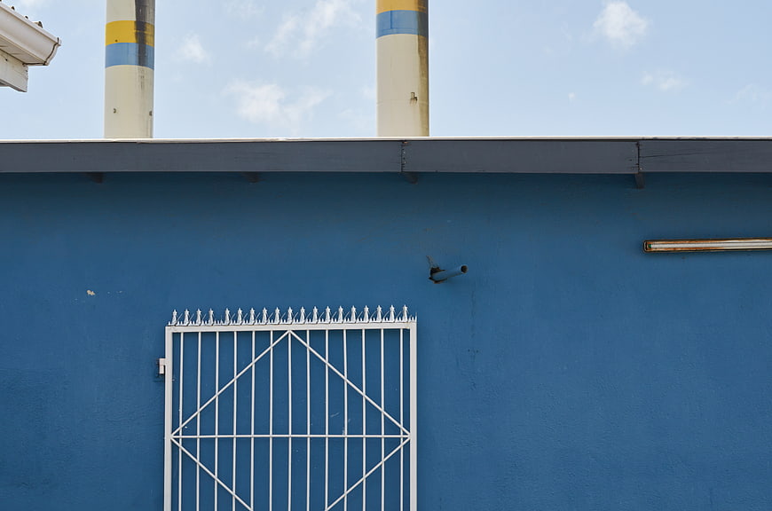 Blue Industrial Wall with White Gate and Smokestacks