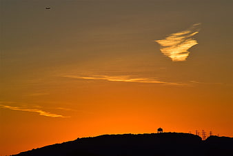 Silhouette of Water Tower on Hill Against Orange Sunset Sky